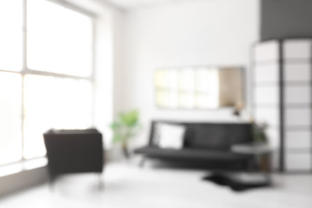Blurred view of room with stylish sofa and mirror on light wallの写真素材