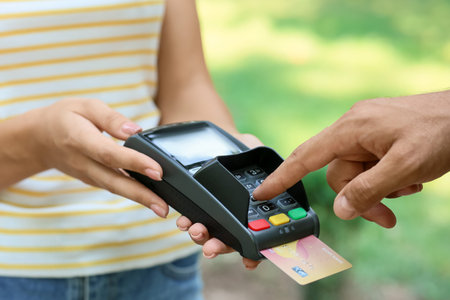 Man paying with credit card via payment terminal outdoors, closeup