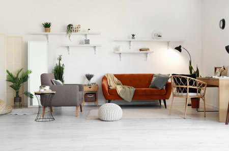 Interior of light living room with modern workplace, red sofa and gray armchairの写真素材