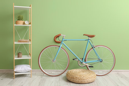 Modern bicycle, pouf and shelving unit near green wallの写真素材