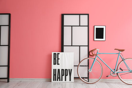 Modern bicycle with poster and folding screen near pink wallの写真素材