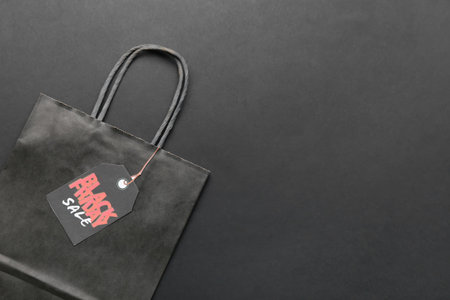 Shopping bag and tag with text BLACK FRIDAY SALE on dark background