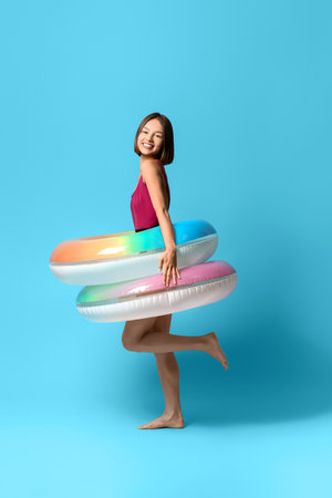 Young woman with inflatable rings on color backgroundの写真素材