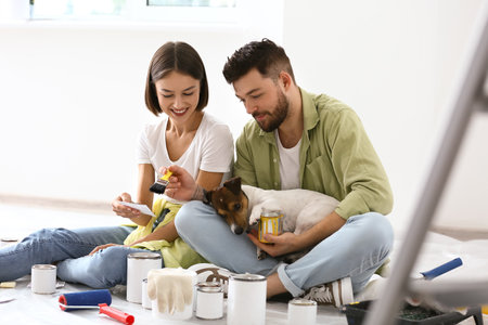 Young couple with cute dog resting during repair of their new houseの写真素材