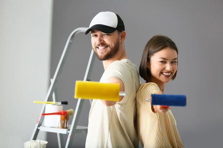 Young couple with paint rollers in their new houseの写真素材