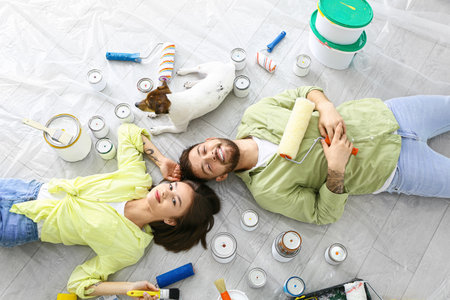 Young couple with cute dog resting during repair of their new houseの写真素材