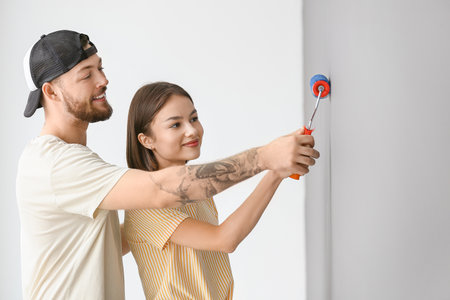 young couple painting wall in roomの写真素材