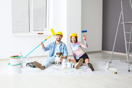 Happy young couple with cute dog resting during repair in their new houseの写真素材