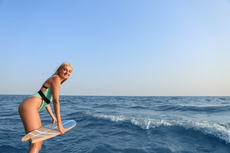 Beautiful young woman with surfboard on sea beach