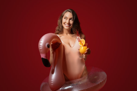 Young woman with cocktail and inflatable ring on color background