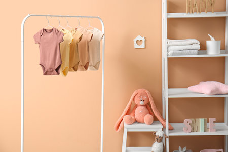 Interior of stylish children's room with rack, baby bodysuits and shelving unitの写真素材