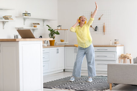 Cool young woman listening to music and dancing at homeの写真素材