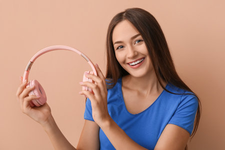 Cool young woman with headphones on color backgroundの写真素材