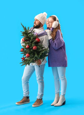 Young couple with christmas tree on blue backgroundの写真素材