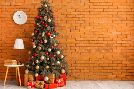 Table with books, lamp, Christmas tree and presents near brick wallの写真素材