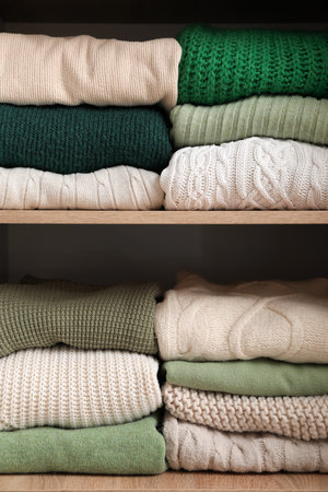 Folded sweaters on shelves in wardrobe, closeupの写真素材