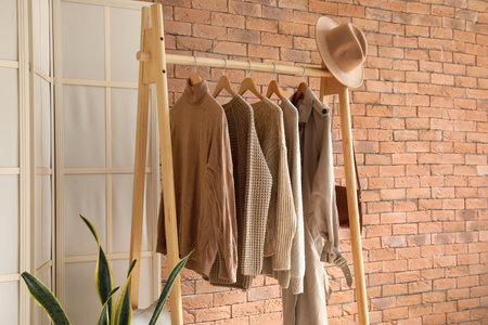 Rack with warm clothes near brick wall in roomの写真素材