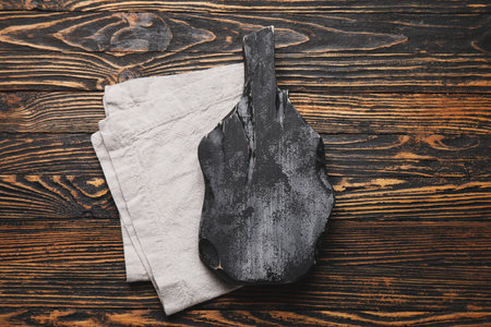 Black cutting board with napkin on dark wooden backgroundの写真素材