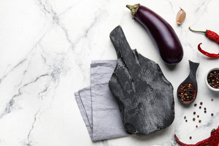 Black wooden cutting board, napkin, spoon with spices and eggplant on grunge backgroundの写真素材