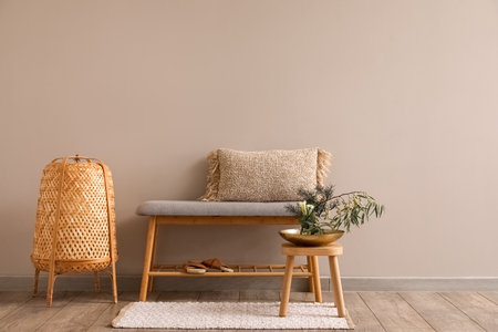 Stool with beautiful ikebana, soft bench and lamp near light wallの写真素材
