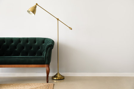 Elegant green sofa and standing lamp near light wallの写真素材