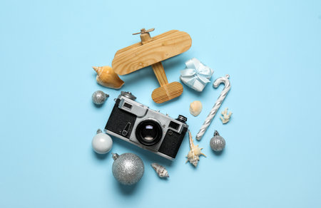 Wooden airplane with photo camera, seashells and Christmas decor on blue background