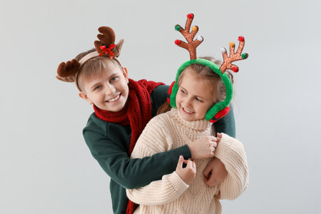 Happy little children in reindeer horns on light backgroundの写真素材