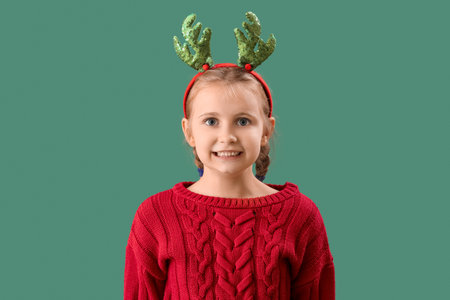 Happy little girl in reindeer horns on green backgroundの写真素材