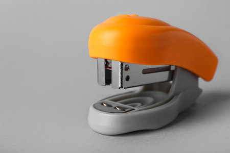 Orange office stapler on gray backgroundの写真素材