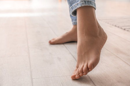 Female bare feet on light wooden floor, closeup