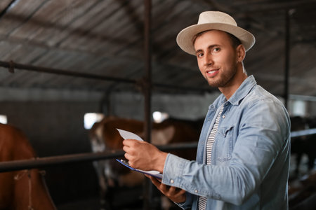 Portrait of young male farmer in cowshedの写真素材