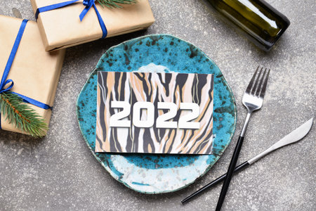 Table setting with greeting card for New Year 2022 celebration on grunge background