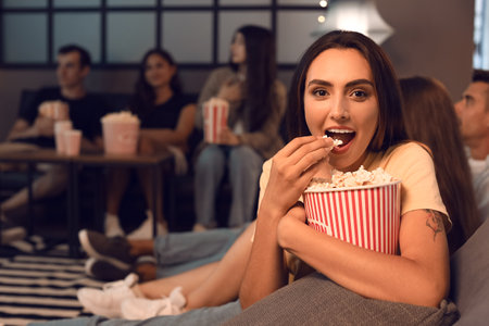 Young woman with popcorn watching movie at home in the eveningの写真素材