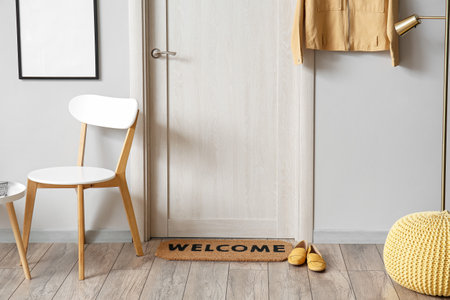 Stylish mat and female shoes near light door in hallway