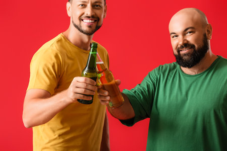 Men drinking beer on red backgroundの写真素材