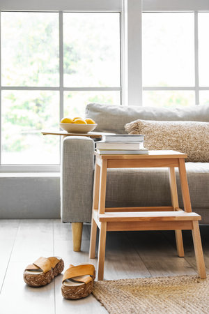 Wooden step ladder with sofa, books and female shoes in interior of living room