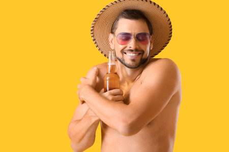 Handsome man with beer on yellow backgroundの写真素材