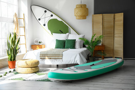 Stylish interior of light bedroom with boards for sup surfingの写真素材