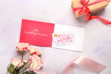 Gift card, flowers, present and ribbon on light background