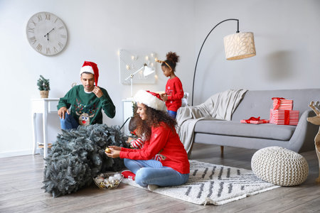 Happy family with children decorating Christmas tree at homeの写真素材