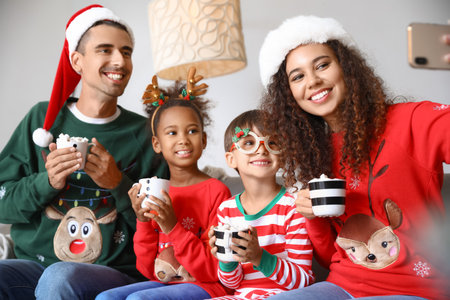 Happy family with cups of hot cocoa taking selfie at home on Christmas eveの写真素材
