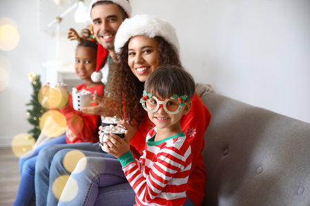 Happy family with children drinking hot cocoa at home on Christmas eveの写真素材