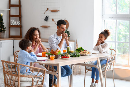 Happy family praying before having Christmas dinner in the kitchenの写真素材
