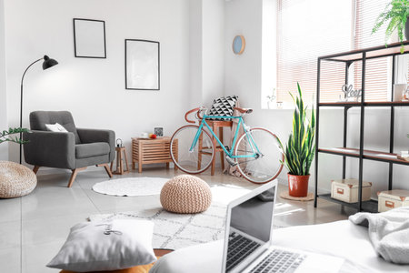 Interior of light bedroom with bicycle, chairs and poufの写真素材