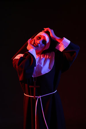 Woman dressed for Halloween as nun on dark background