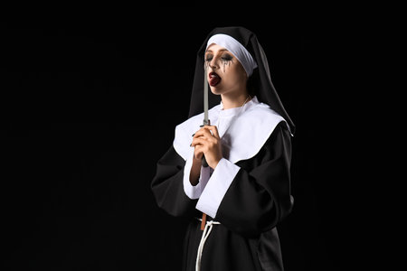 Woman dressed for Halloween as nun with knife on dark backgroundの写真素材