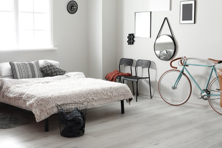 Interior of light bedroom with modern bicycle and chairsの写真素材