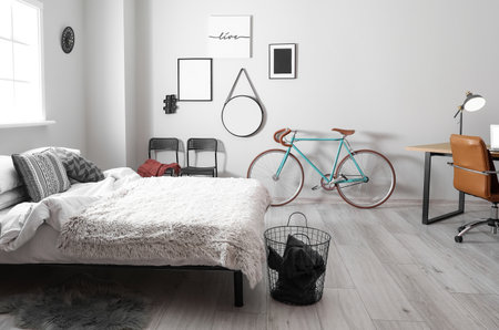 Interior of light bedroom with bicycle and modern workplaceの写真素材