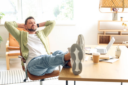 Handsome man relaxing at table in officeの写真素材