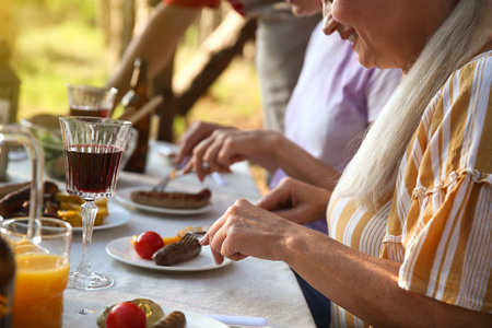 Mature woman eating grilled food at barbecue partyの写真素材